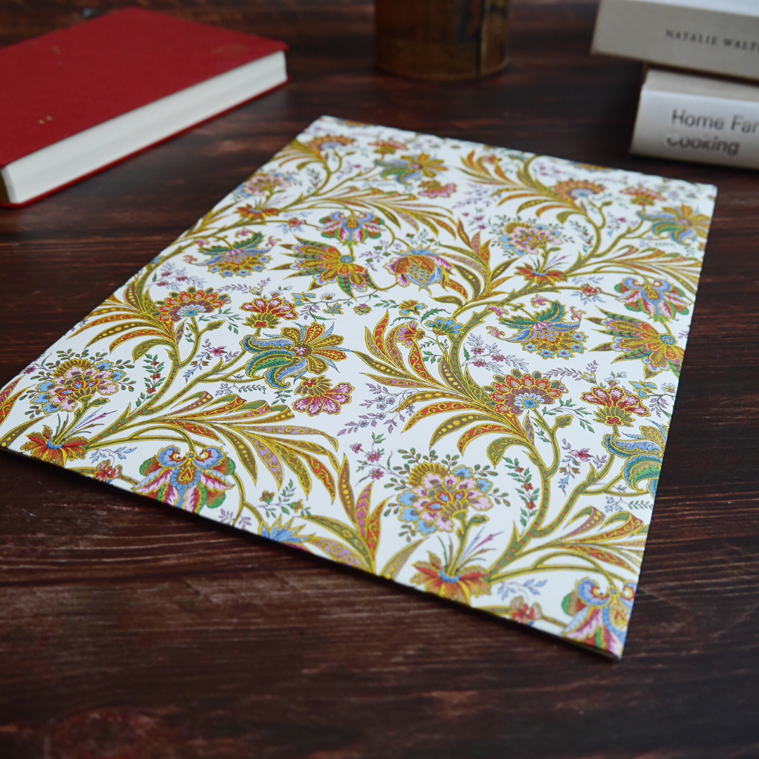 Cipro柄の便箋と封筒を木のテーブルに配置。柔らかな光にきらめく金粉印刷が魅力。