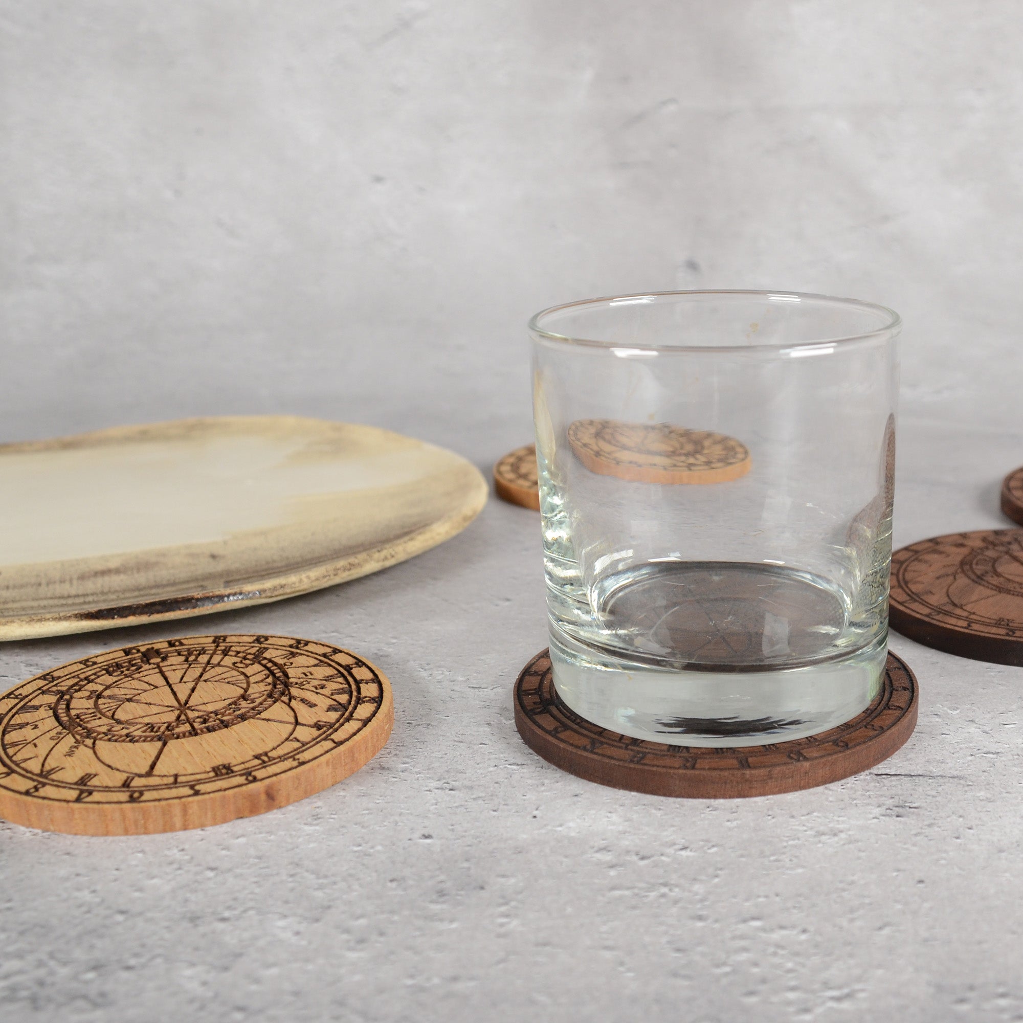 天文時計の木製コースターにグラスを載せた使用イメージ|食卓に映える天文時計のモチーフ