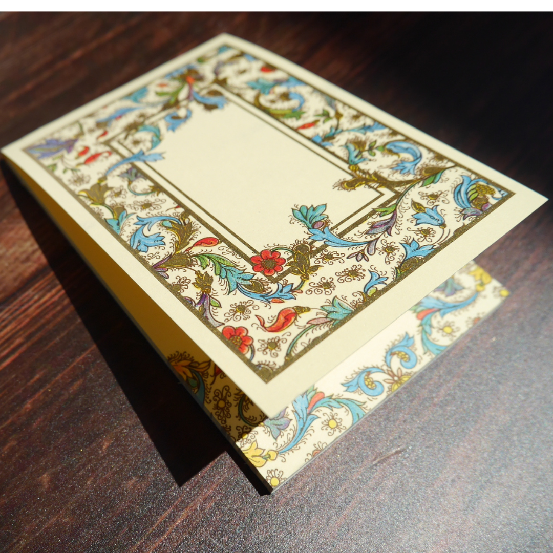 木の上に置かれたKartosのMedicea柄メモ。金粉が光を受けて上品にきらめく美しい紙面。