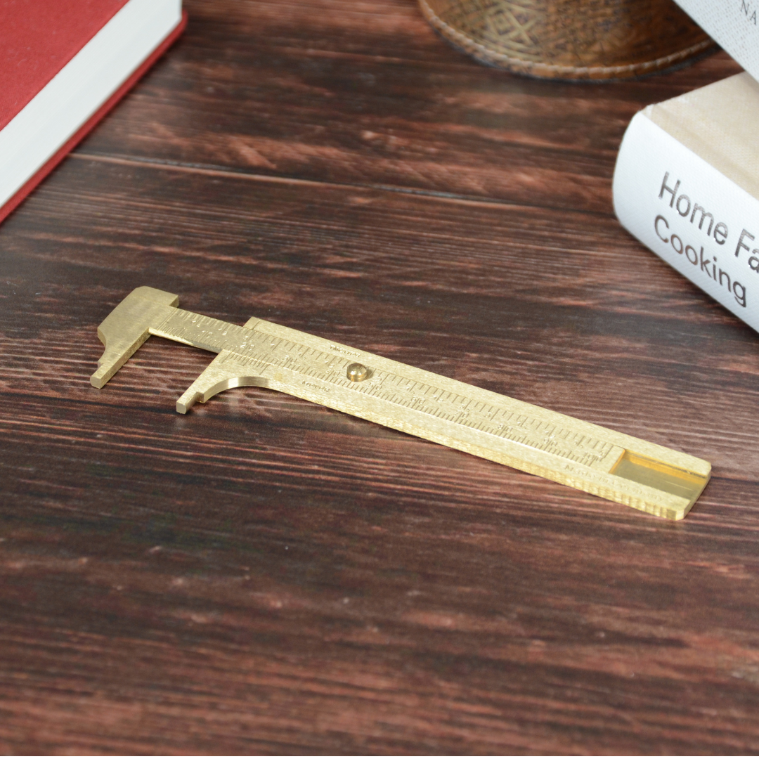 木のテーブルに置かれた真鍮ノギス。ヴィンテージ感のあるライフスタイル風写真