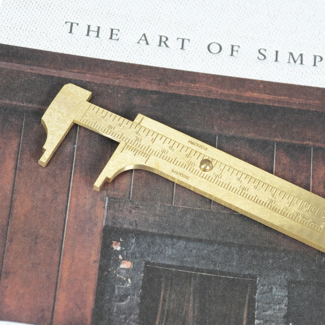 アンティーク調の本とともに置かれた真鍮ノギス。クラシックな雰囲気のカット